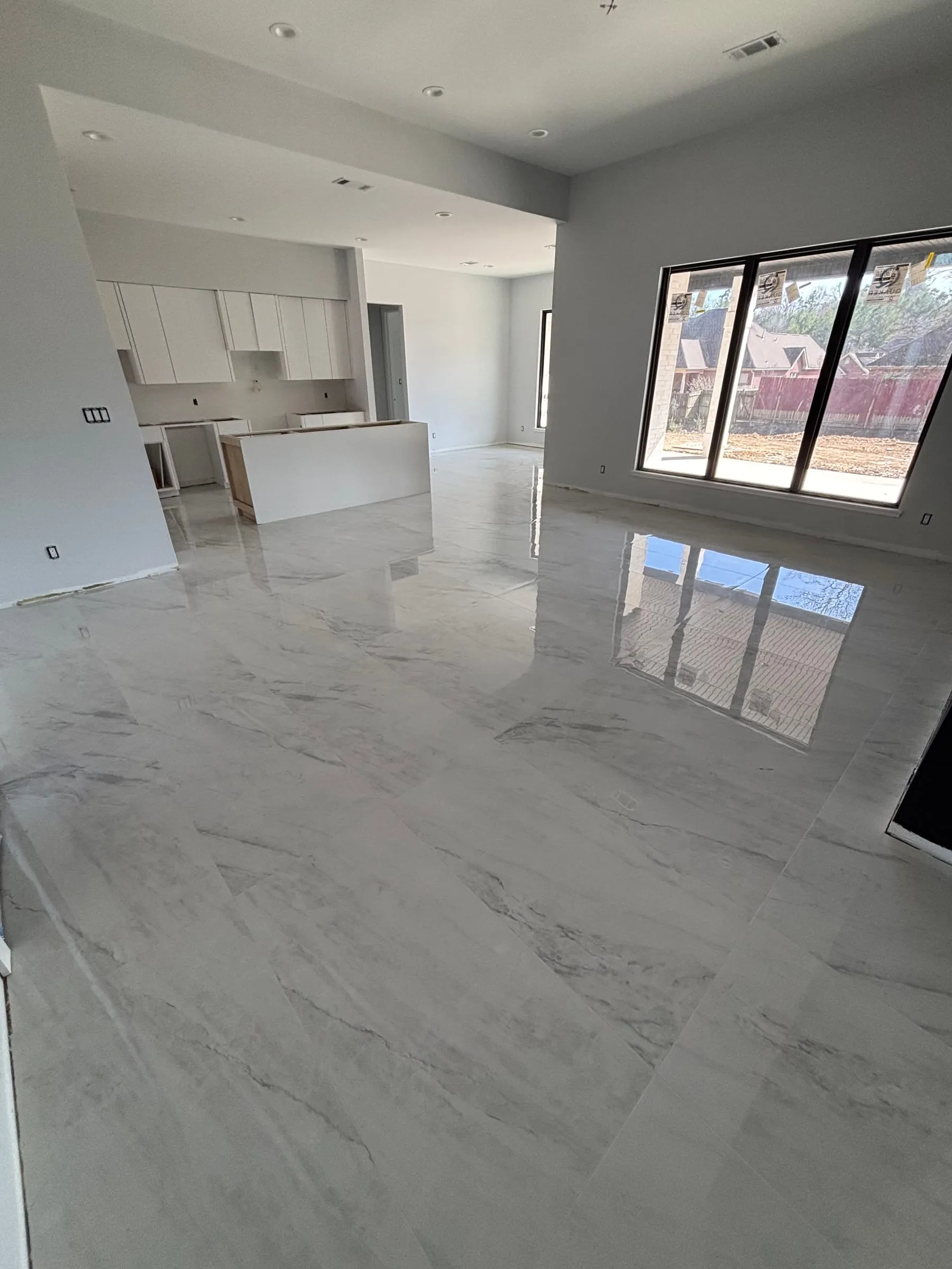 Open living area and kitchen floored in large polished marble-look porcelain