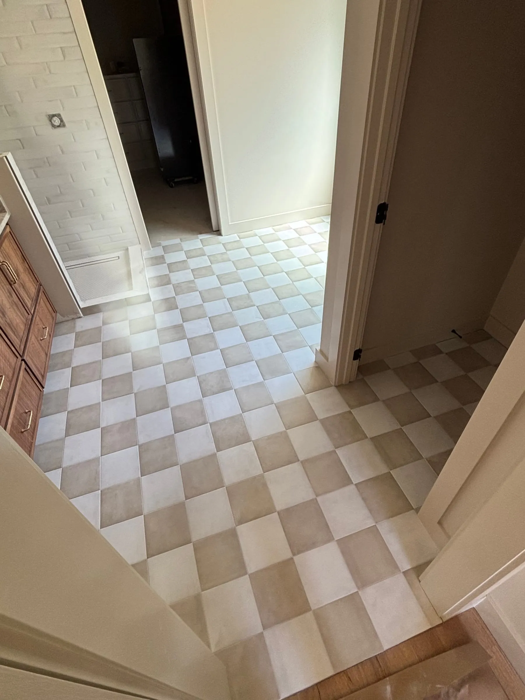 Cream and beige checkerboard floor tile running through a bathroom doorway
