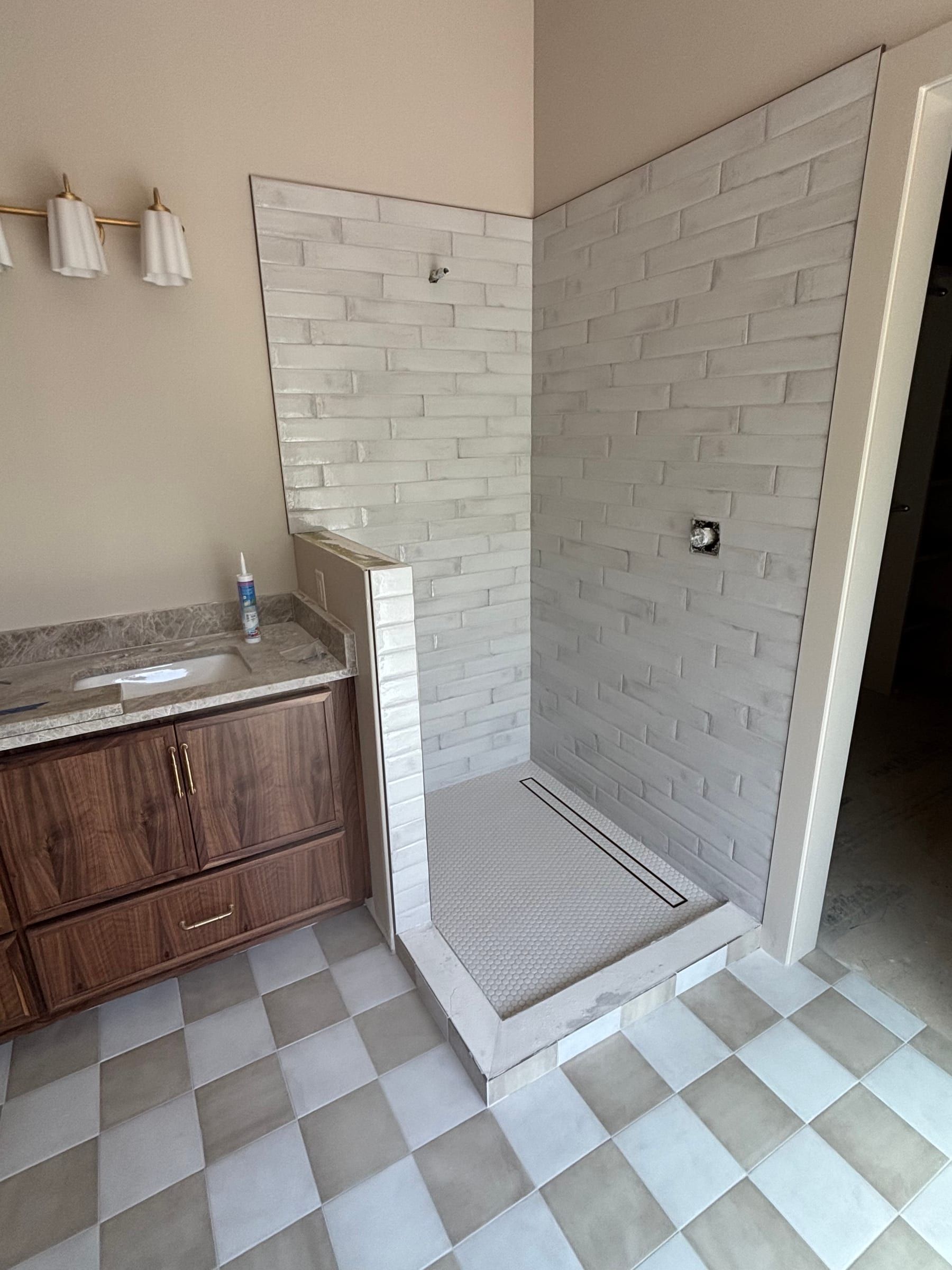 Bathroom with a checkerboard floor and a curbless shower in glossy white subway tile