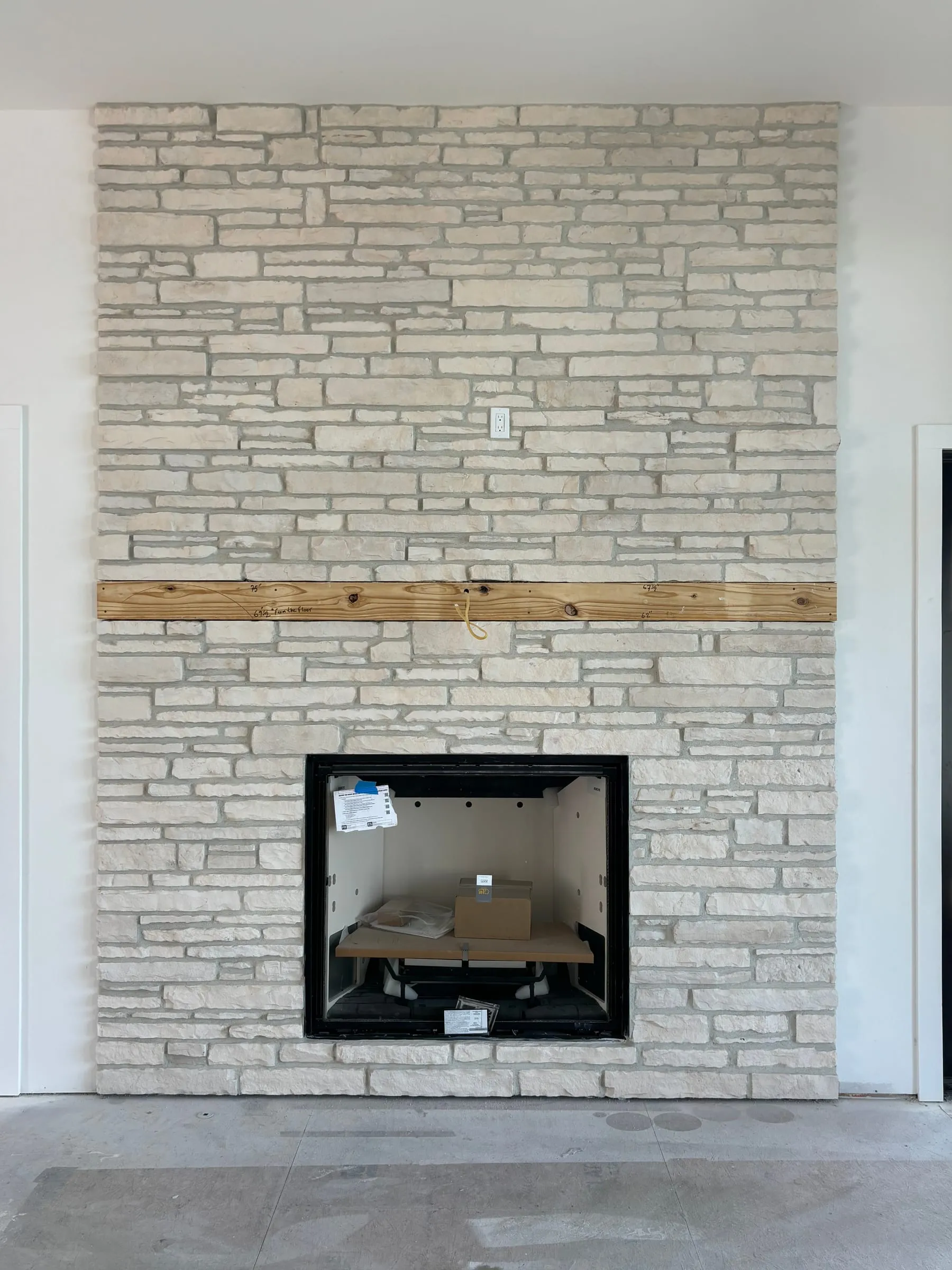Fireplace wall clad floor to ceiling in light stacked-stone veneer