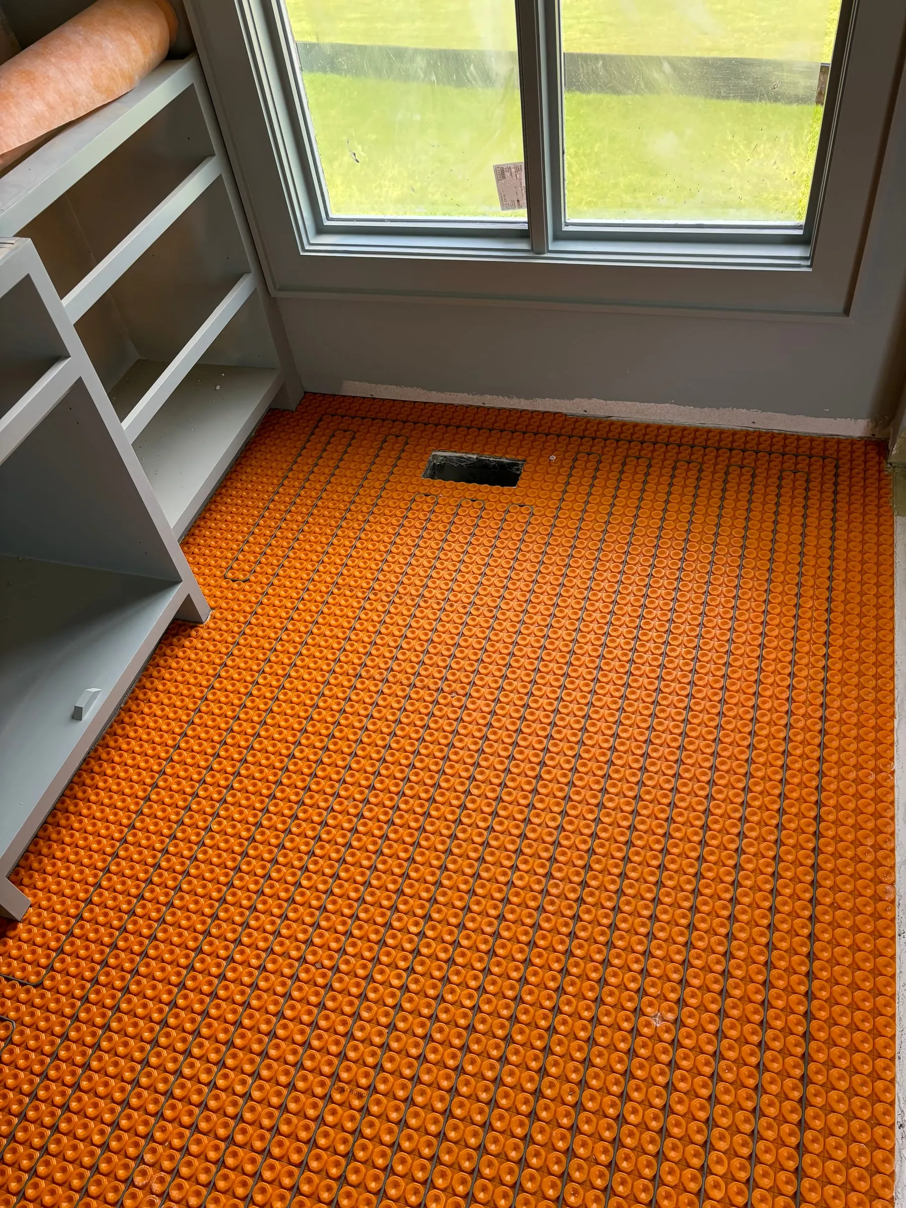 Orange uncoupling membrane laid over the subfloor before tile