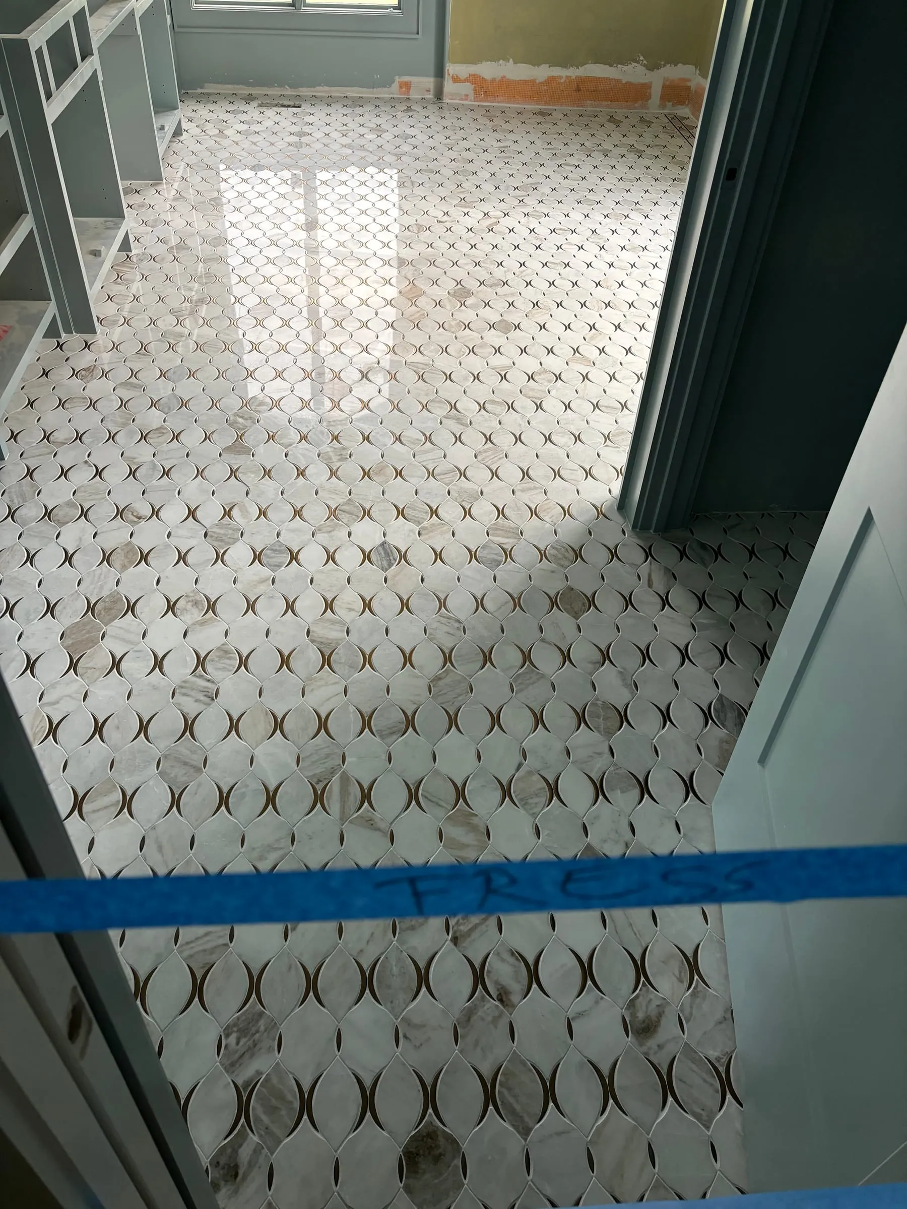 White marble mosaic floor with dark accent inlays, protected during construction