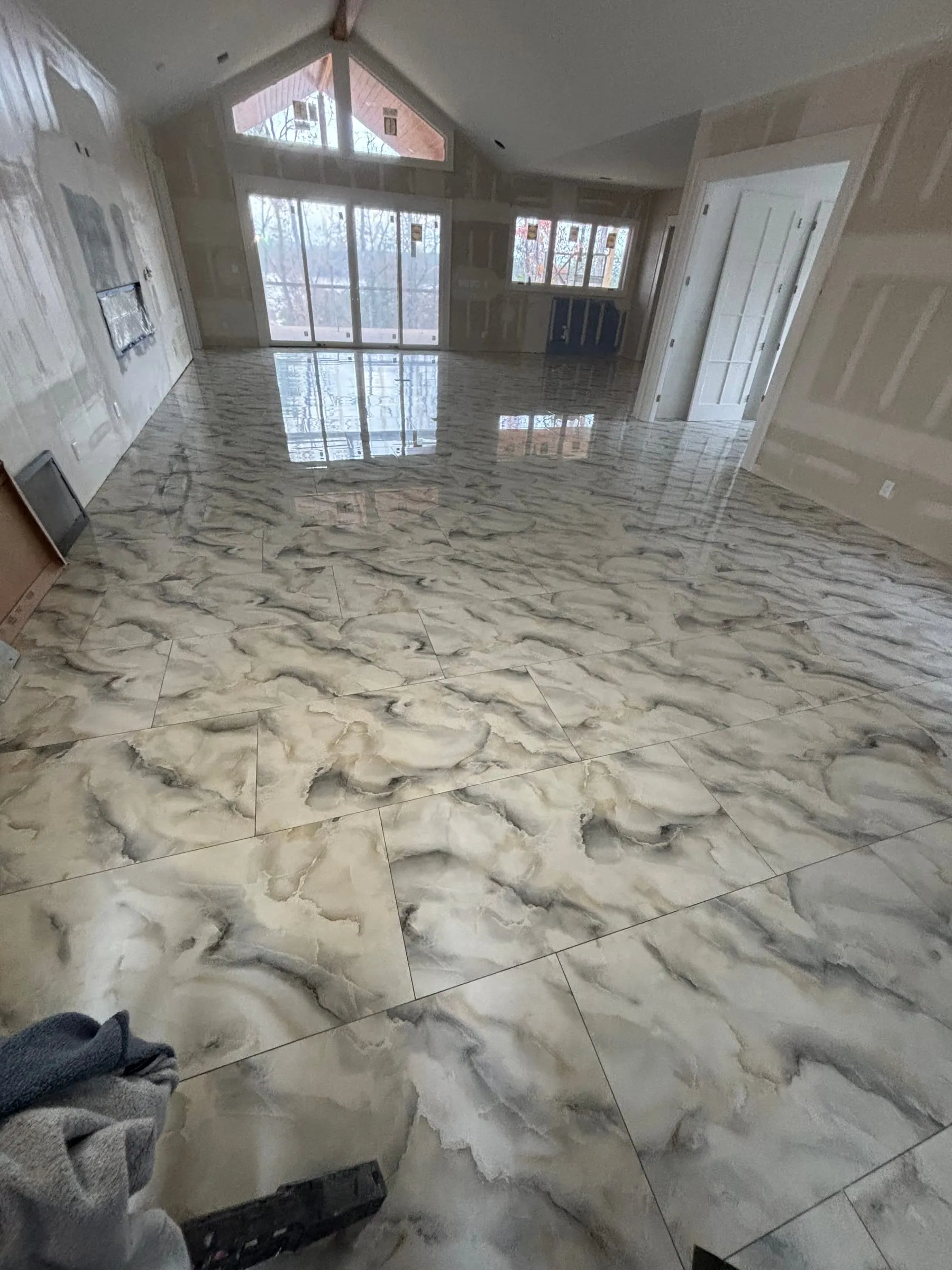 Large living room floored in polished marble-look porcelain with bold gray veining