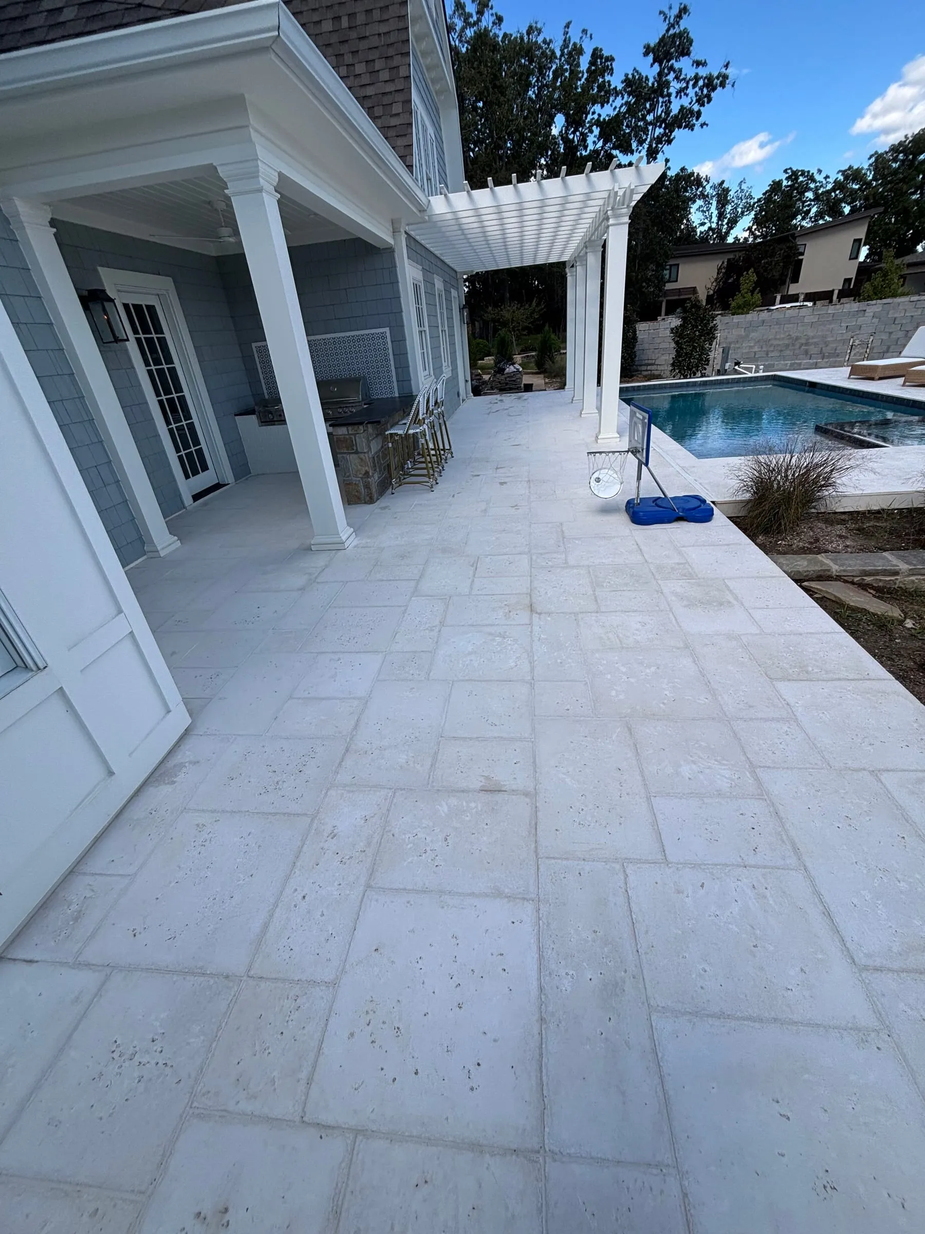 White paver pool deck and patio beside a covered porch