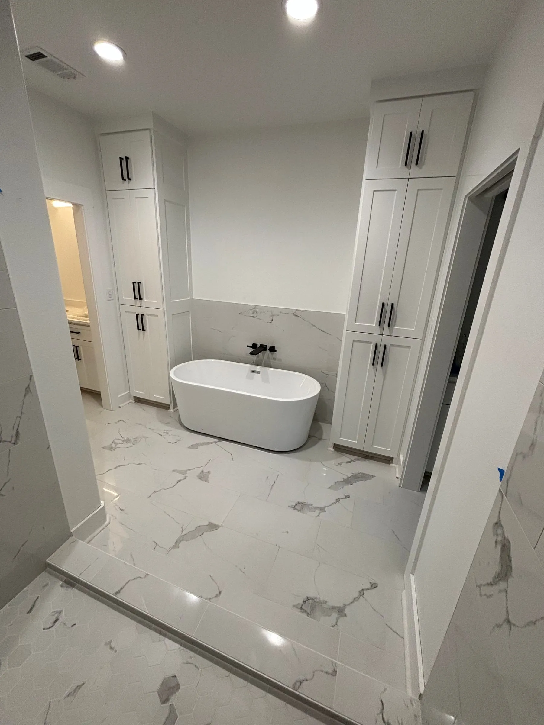 Bathroom with a freestanding tub and large marble-look floor tile