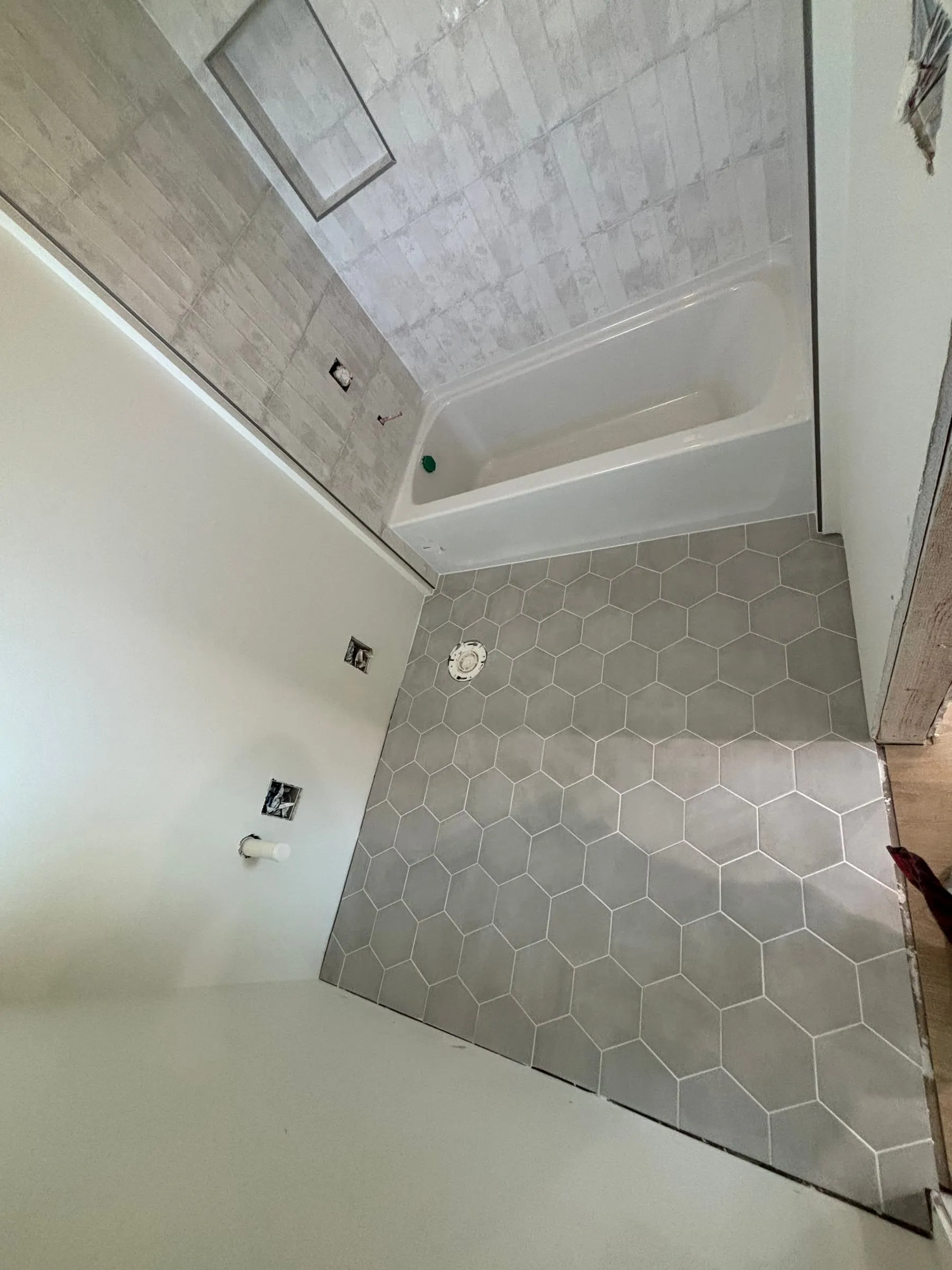 Bathroom with large gray hexagon floor tile and a tiled tub surround