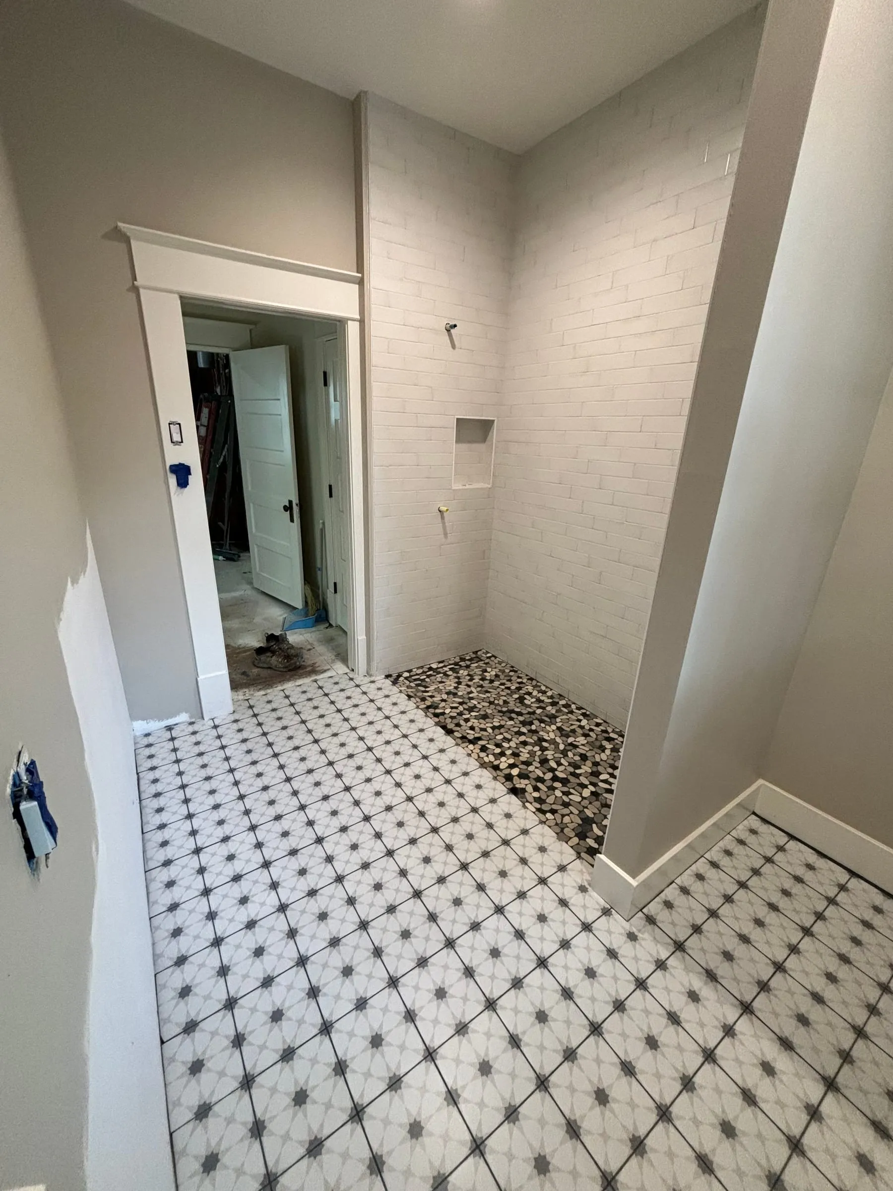 Bathroom floor in white octagon-and-dot tile leading to a pebble shower floor