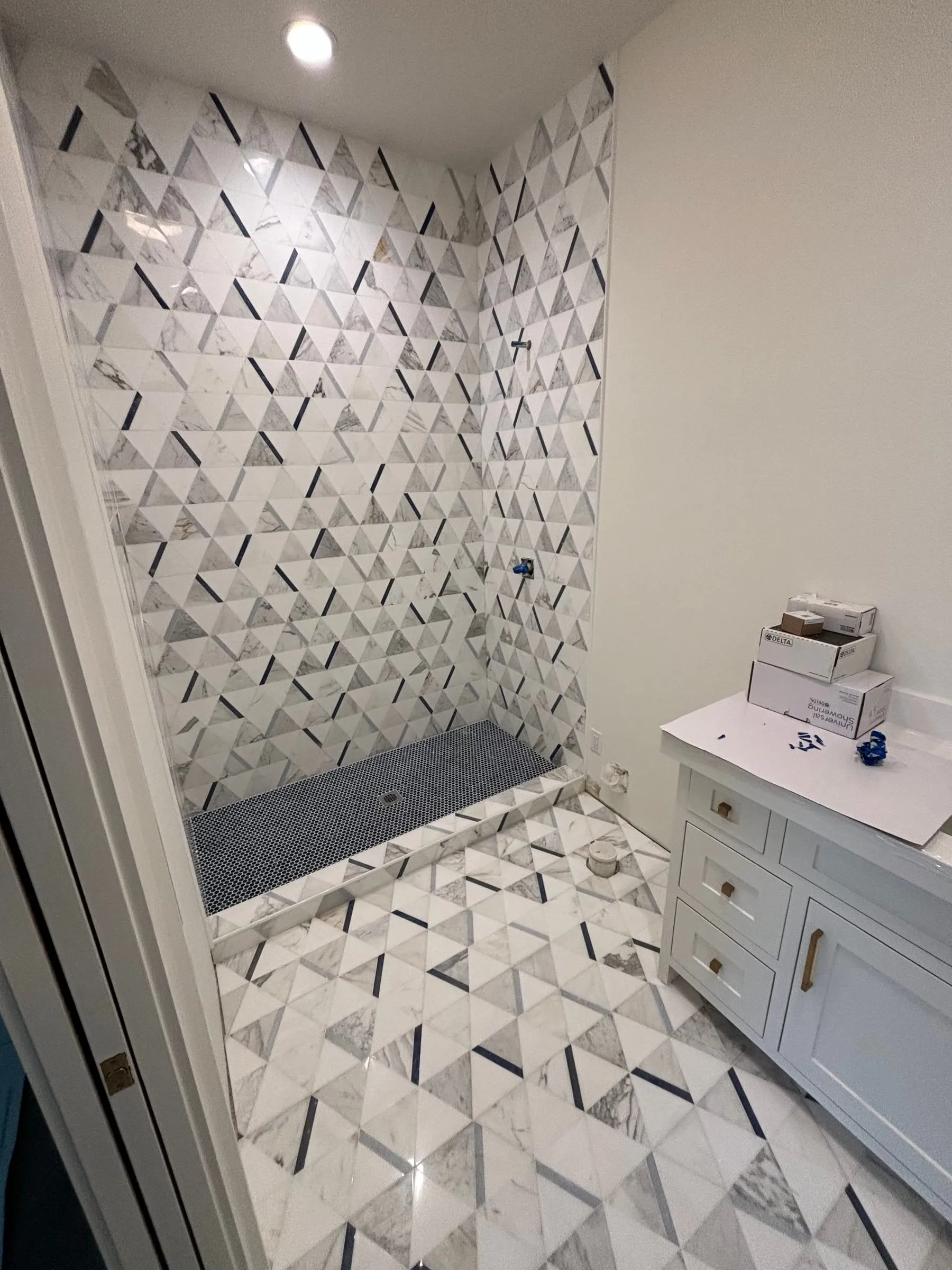 Shower and bathroom floor in a white and gray triangle marble mosaic