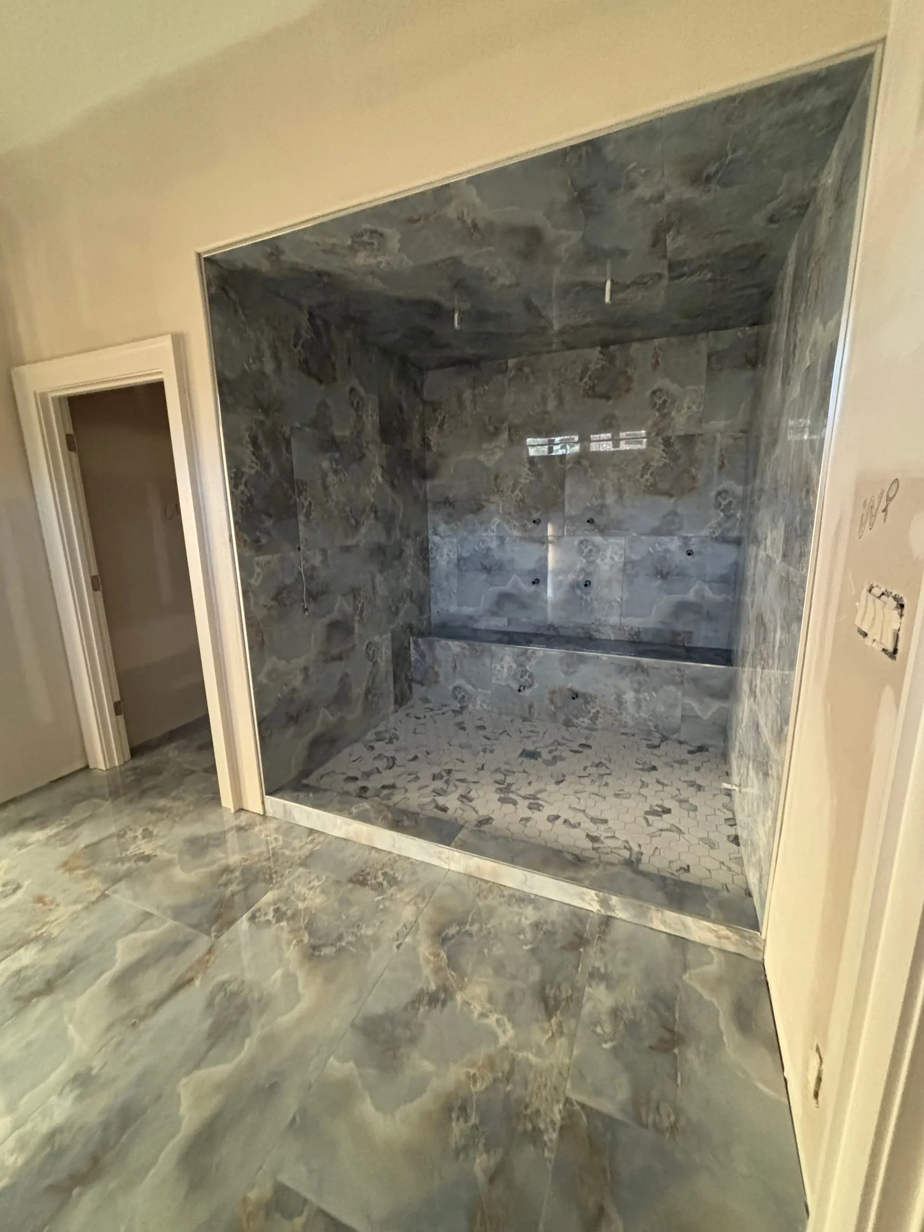 Walk-in shower and floor in large glossy blue-gray onyx-look porcelain