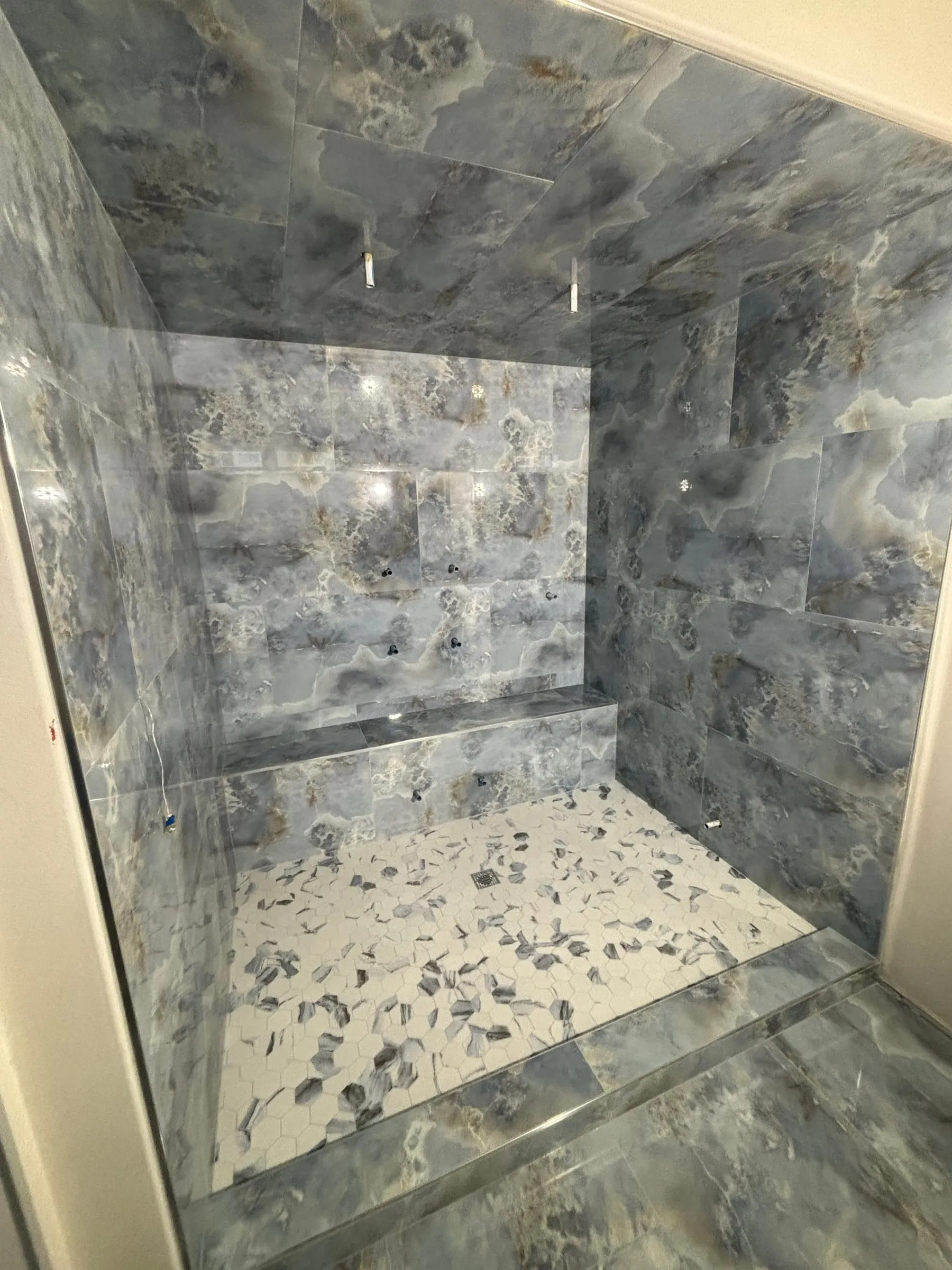 Onyx-look shower with a tiled bench and a mosaic floor