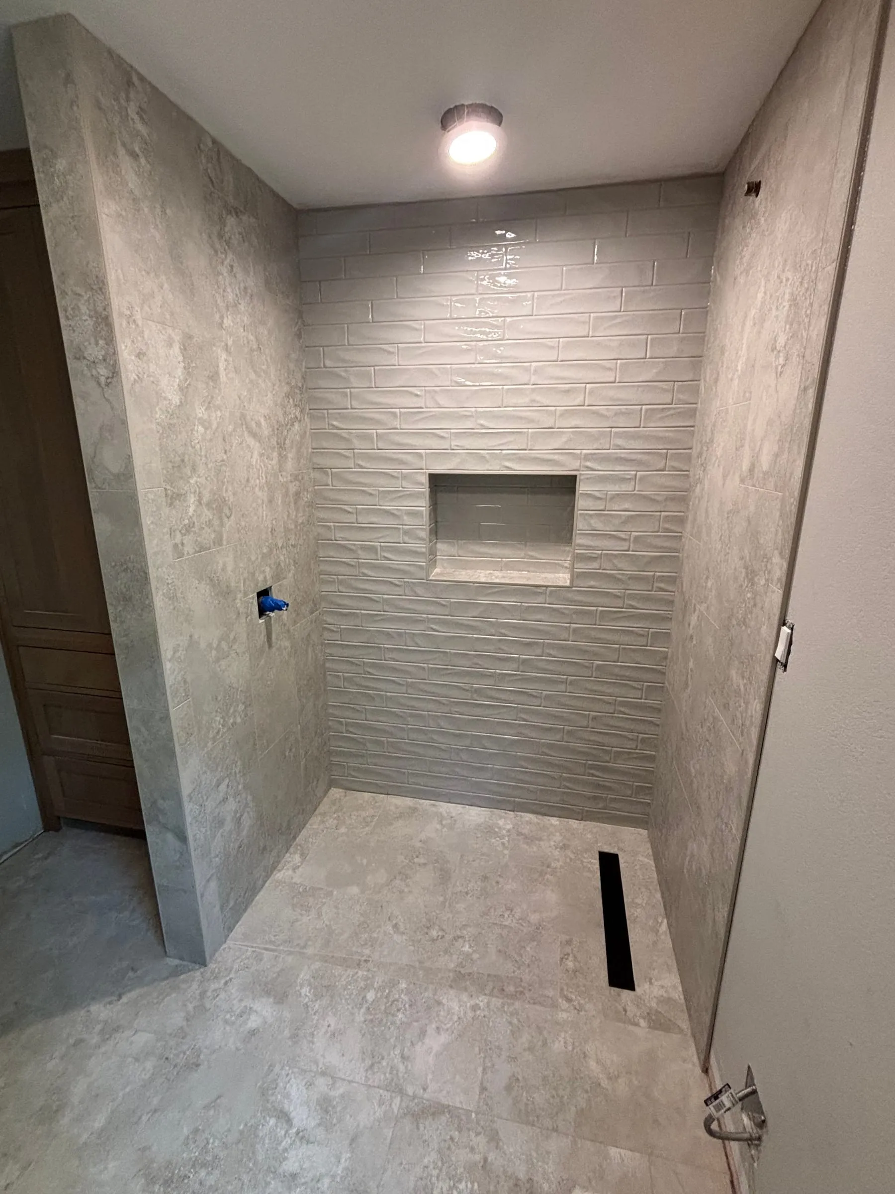 Curbless shower in large stone-look tile with a linear drain and a textured feature wall