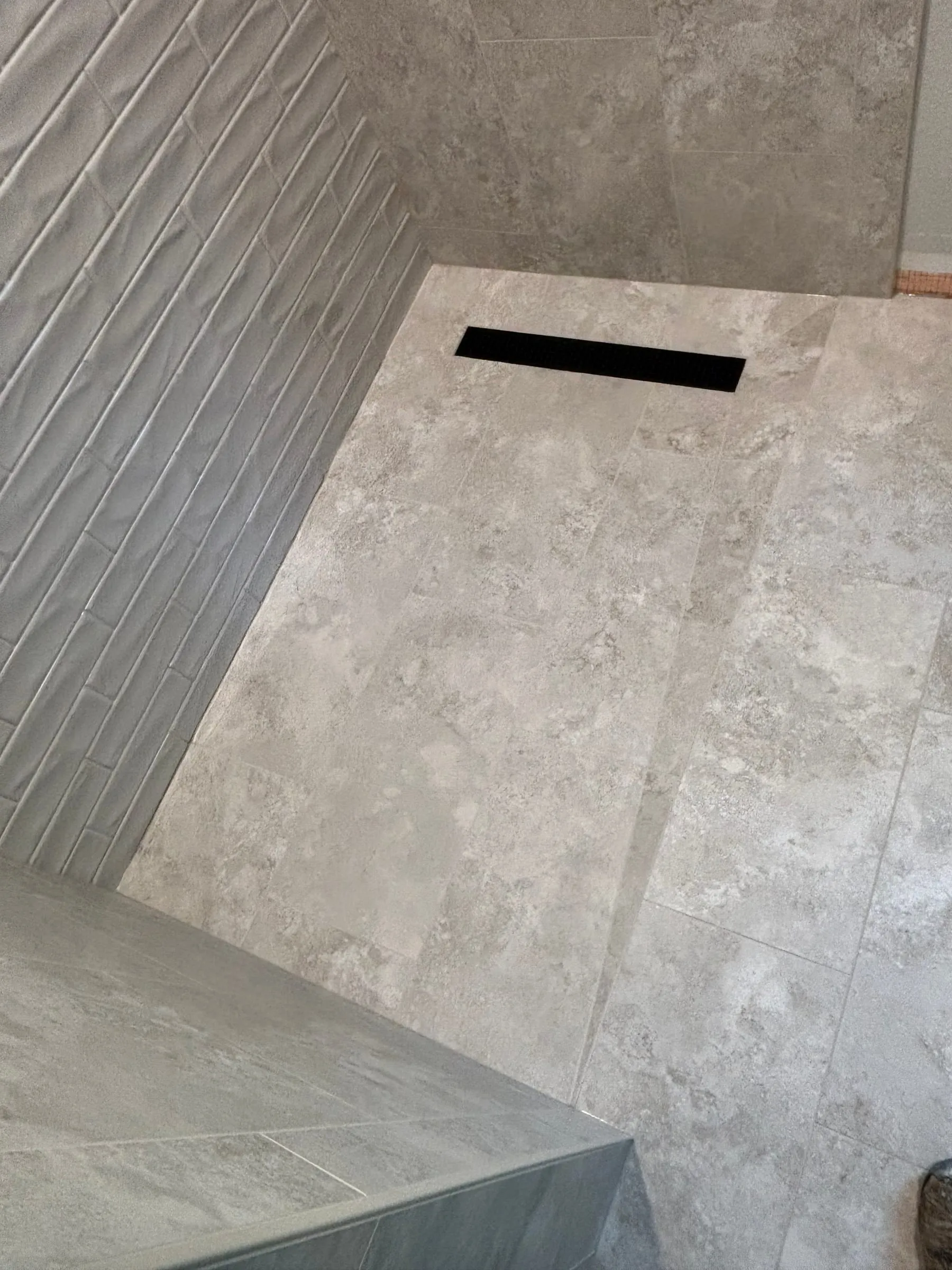 Linear drain in a curbless shower floor of large stone-look tile