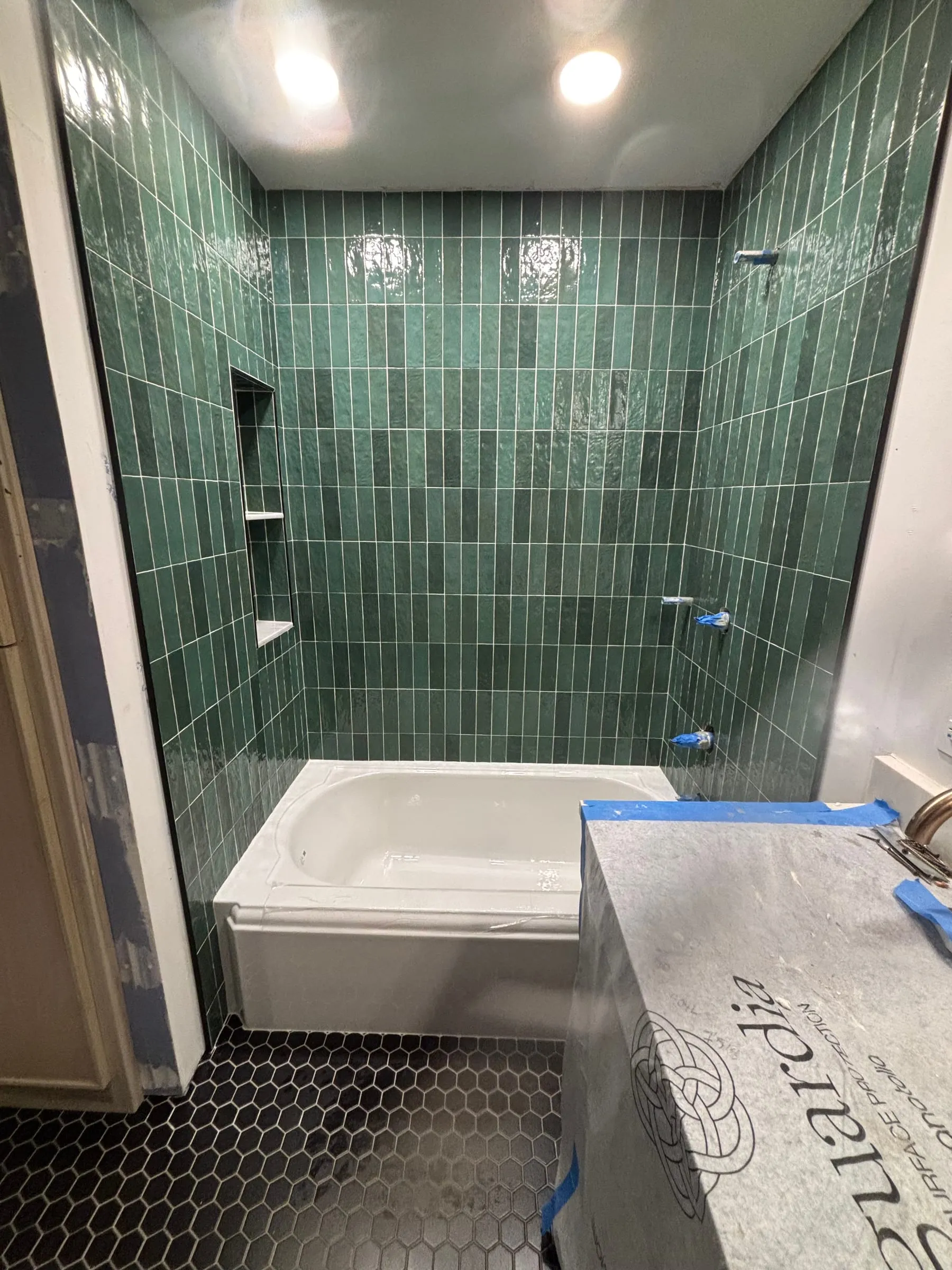 Green tile tub surround with built-in niches, before trim-out