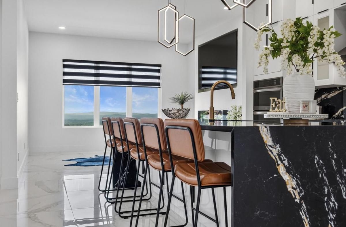 Kitchen island with a black marble waterfall edge and leather bar stools