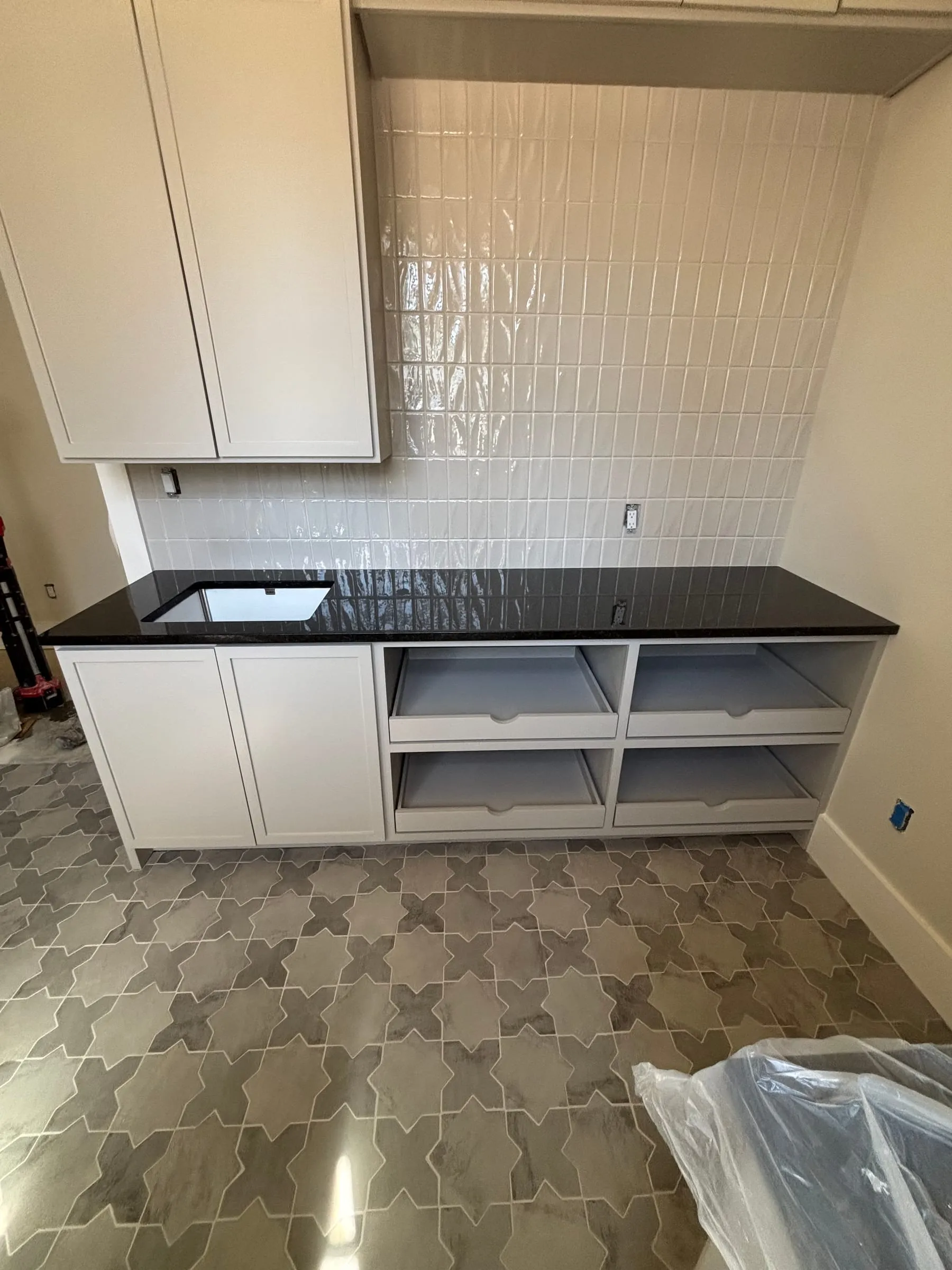 Laundry room with a glossy white vertical backsplash and a gray star-and-cross floor tile