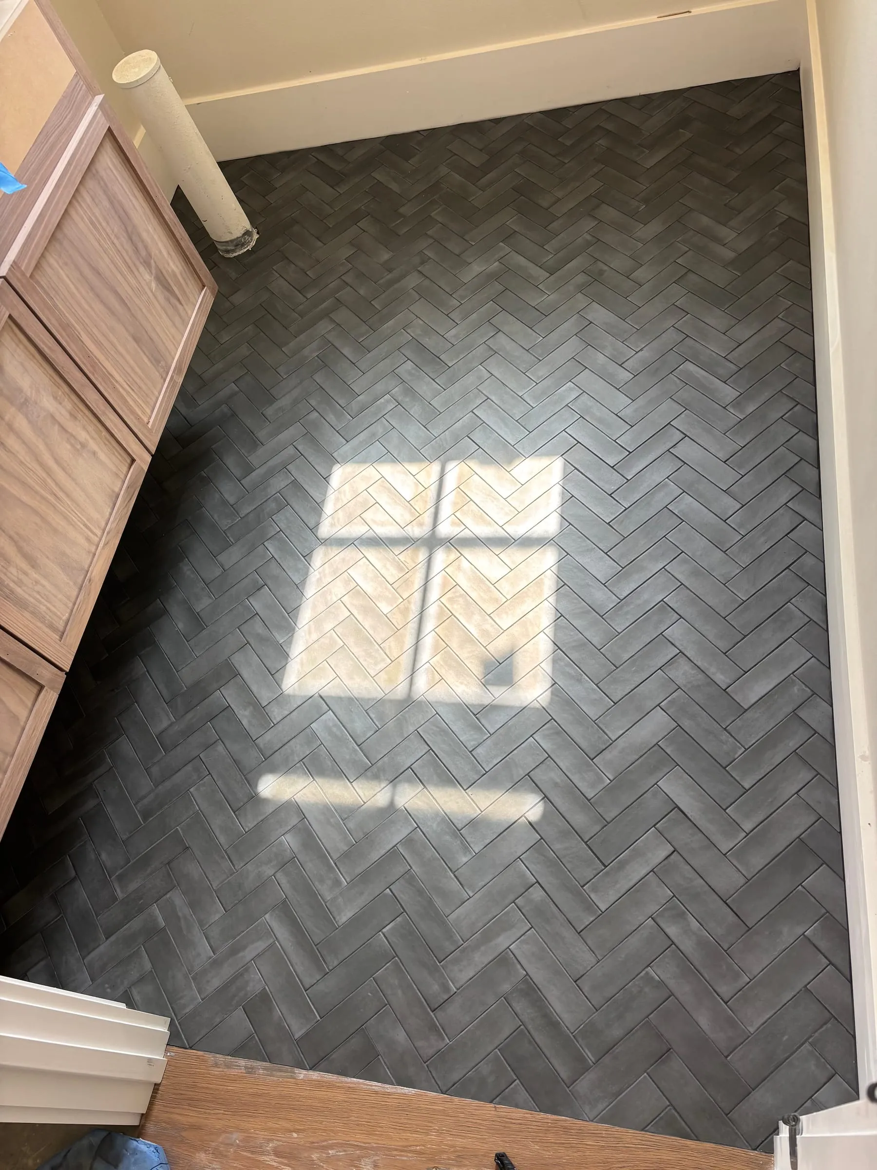Charcoal tile laid in a herringbone pattern on a mudroom floor