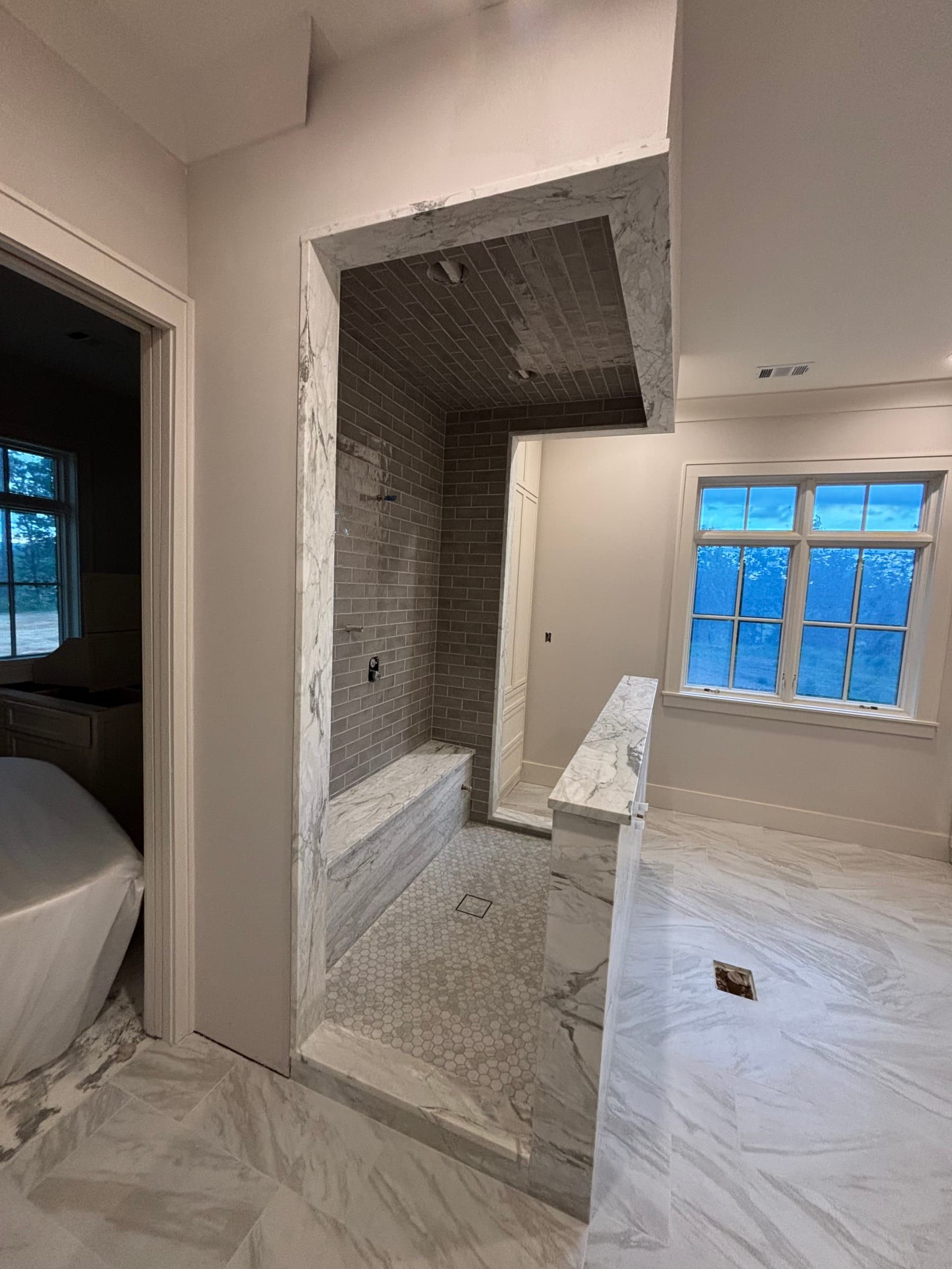 Primary bath with a freestanding tub, walk-in shower, and large marble-look floor tile