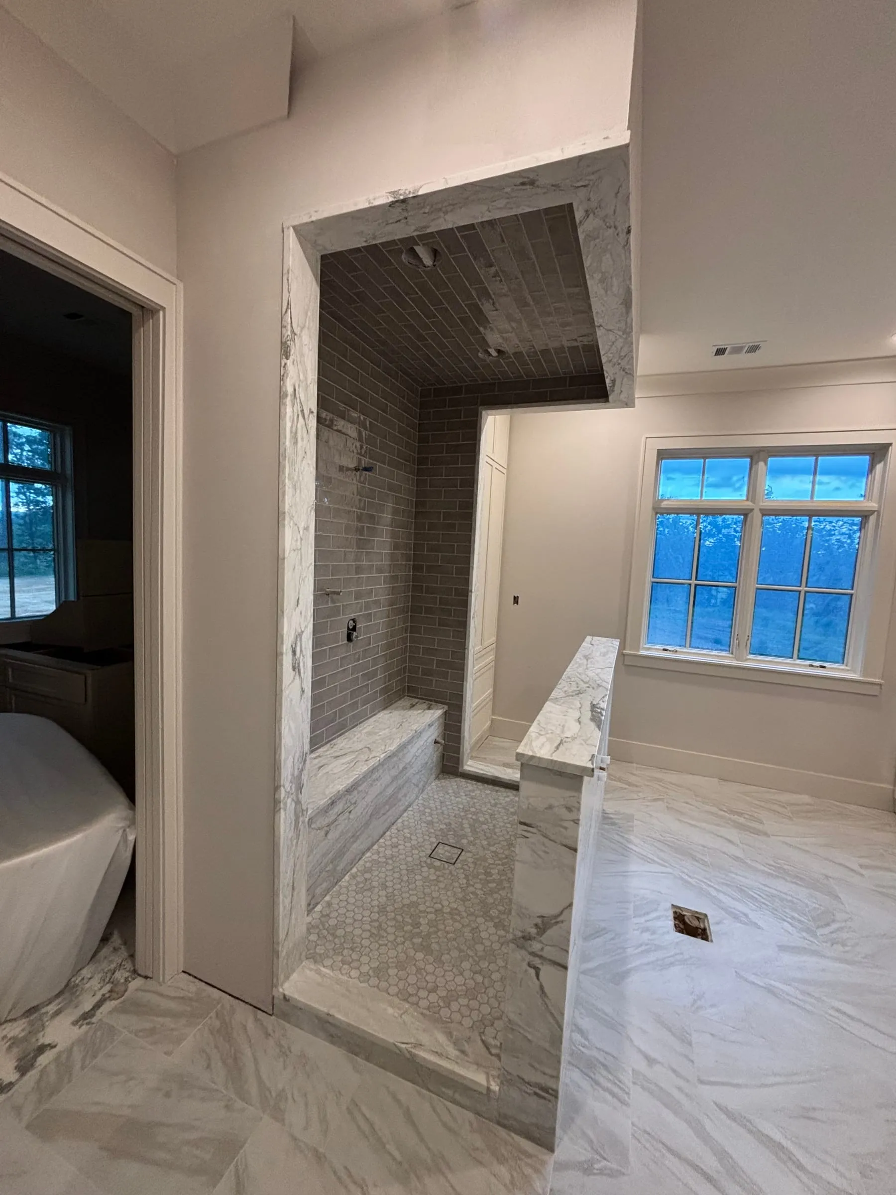 Primary bath with a freestanding tub, walk-in shower, and large marble-look floor tile