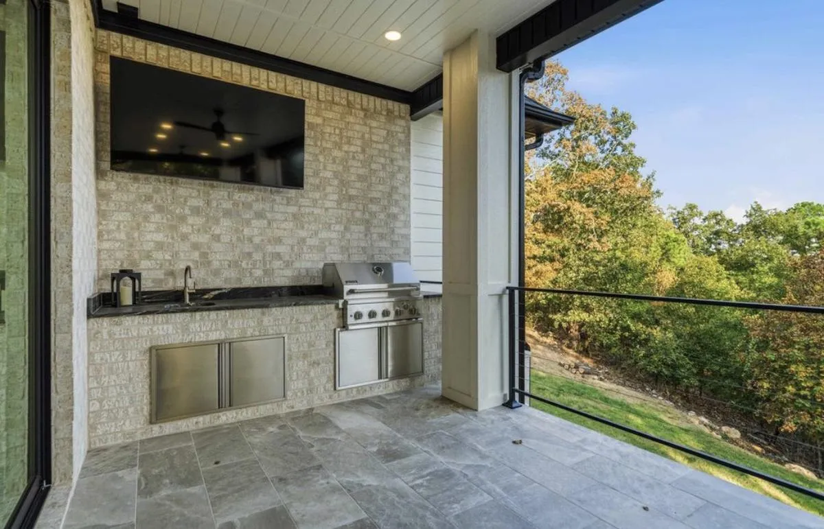 Covered outdoor kitchen with a built-in grill and gray porcelain floor tile