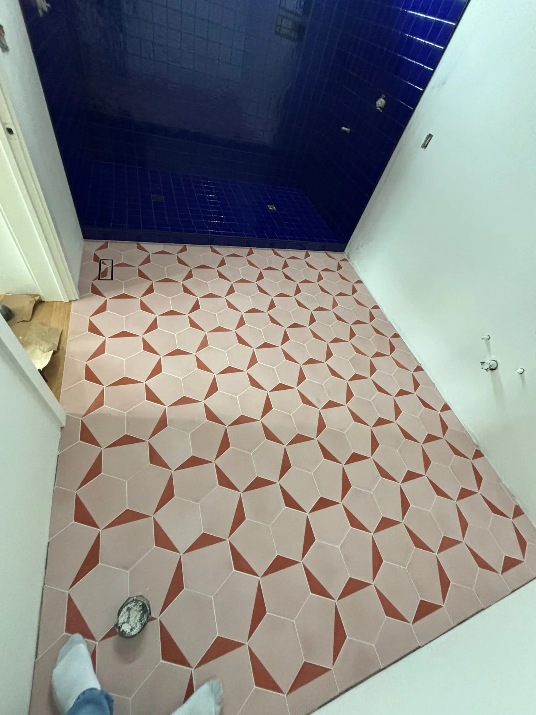 Pink and white star-pattern floor tile in front of the cobalt shower