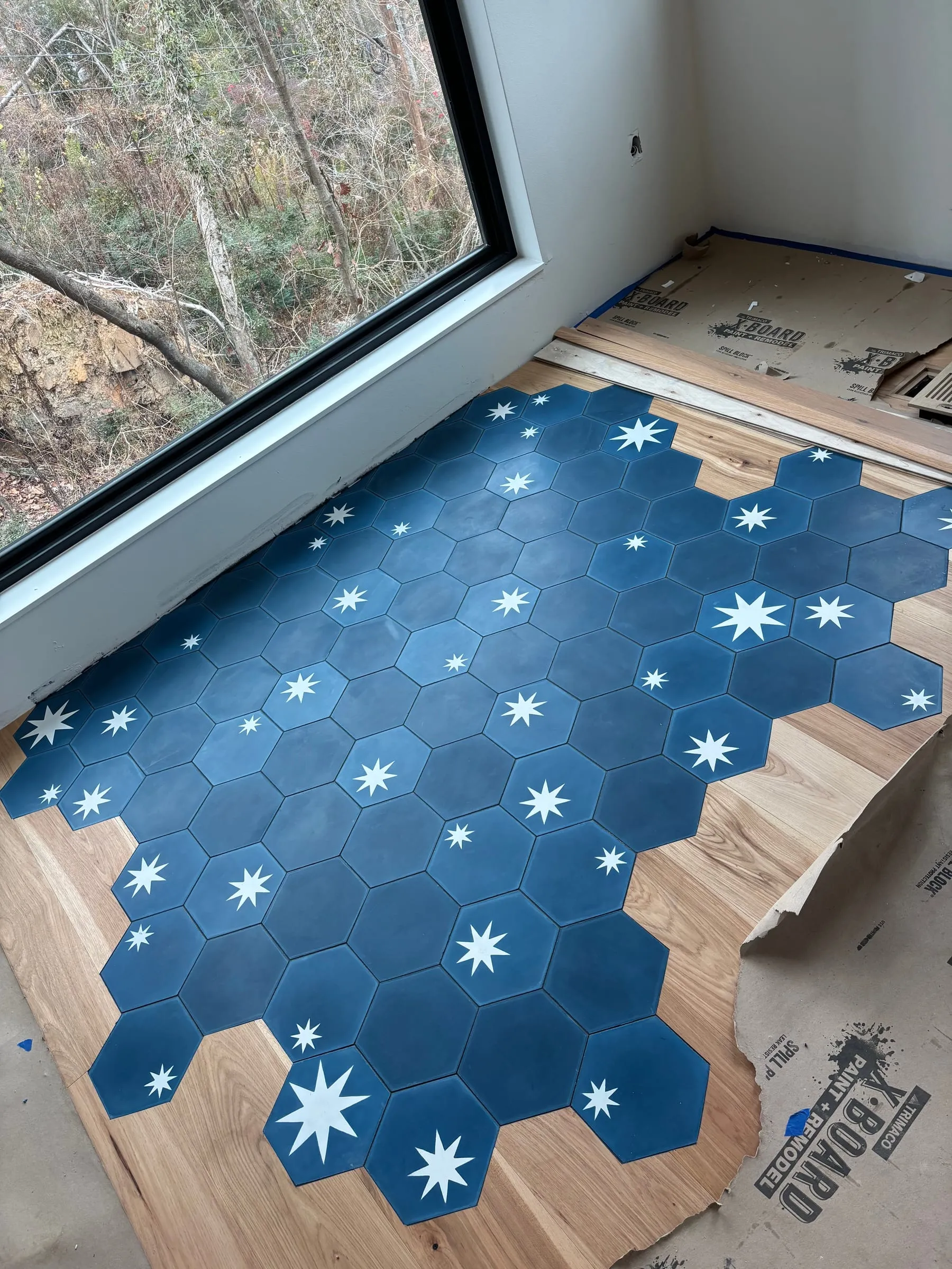 Navy hexagon tiles with white stars inset into a wood floor with a loose, organic edge