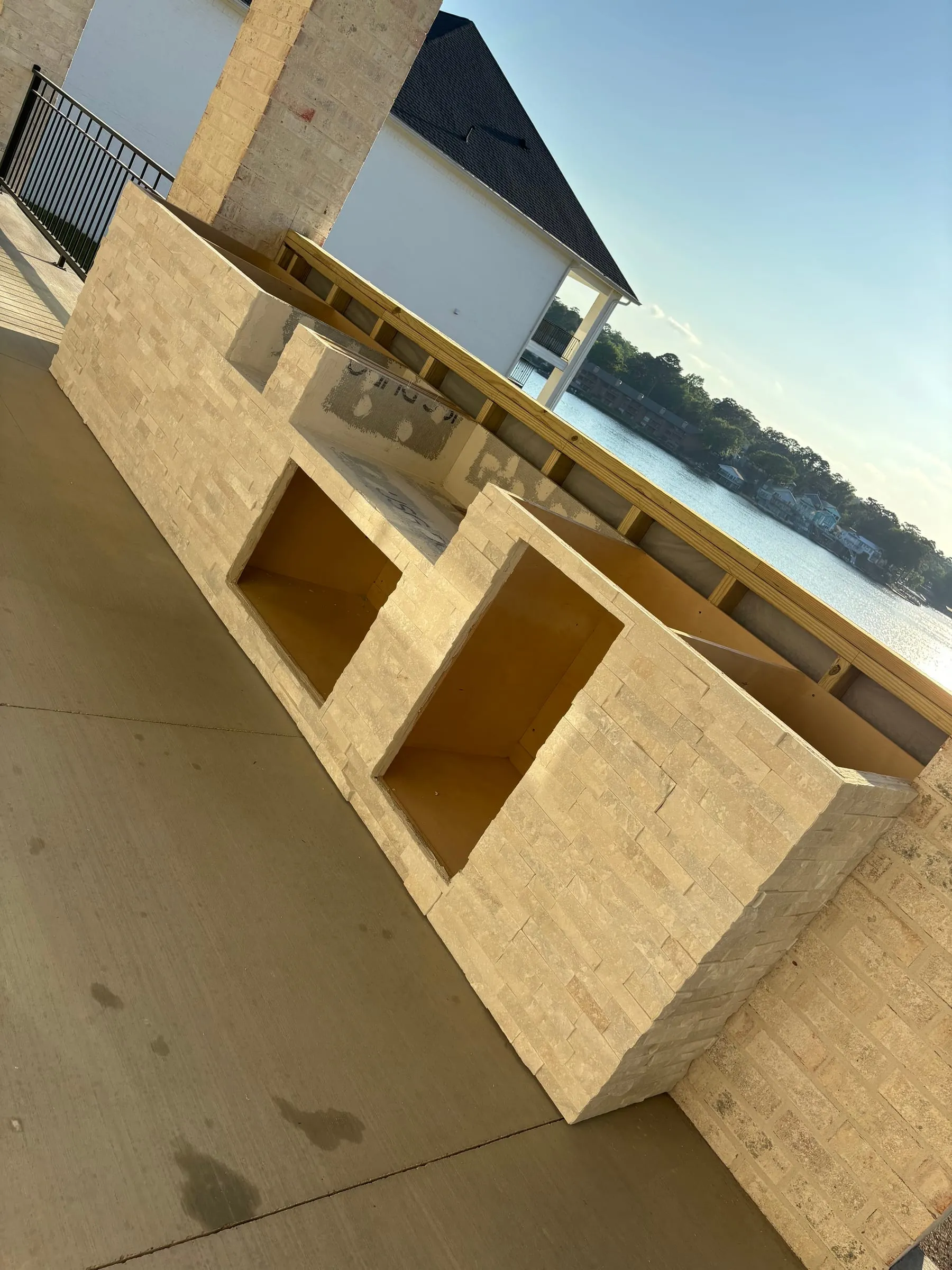 Outdoor kitchen base clad in split-face stone veneer, in progress