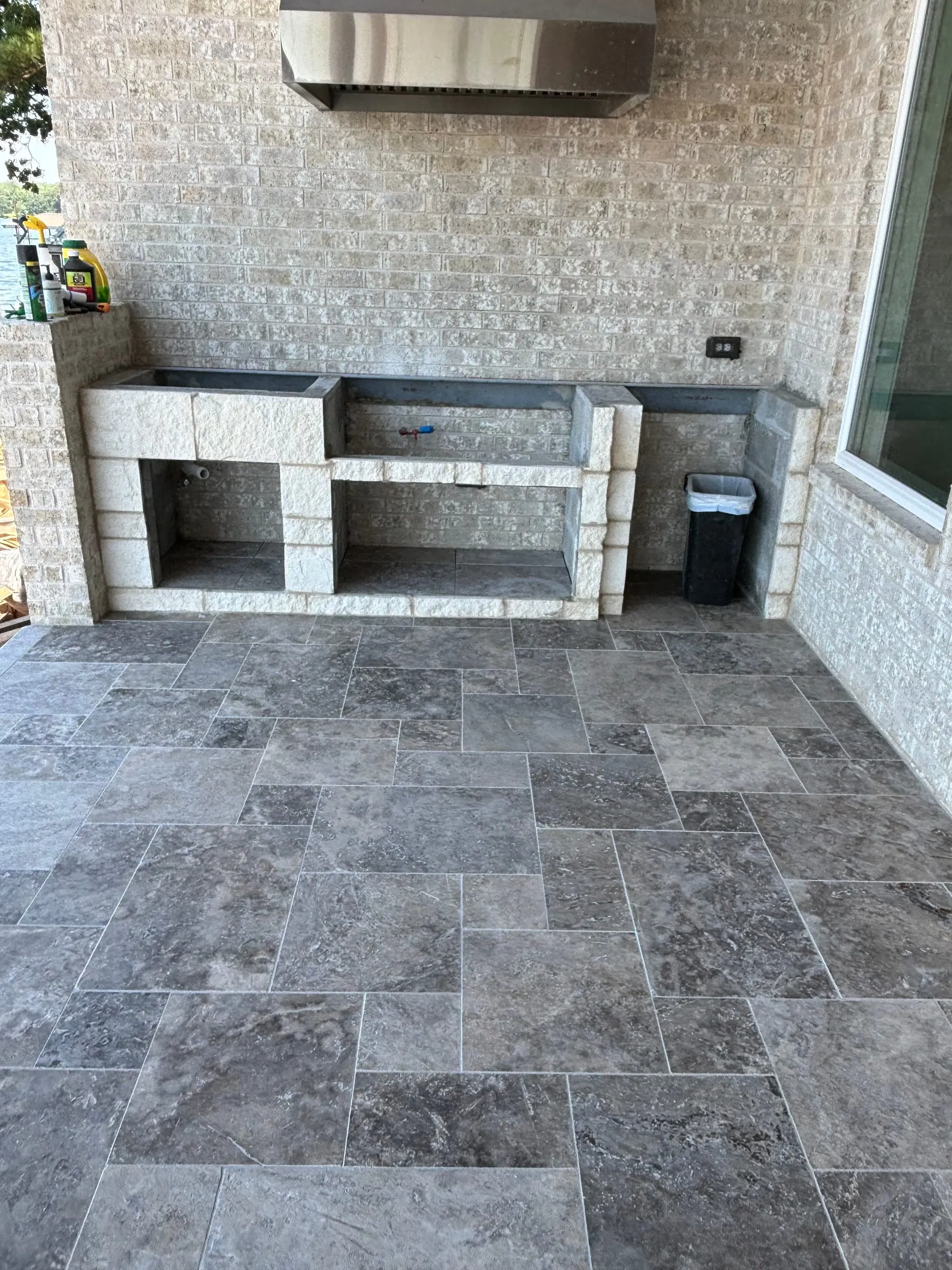 Outdoor kitchen with a stone-veneer counter base on a silver travertine patio