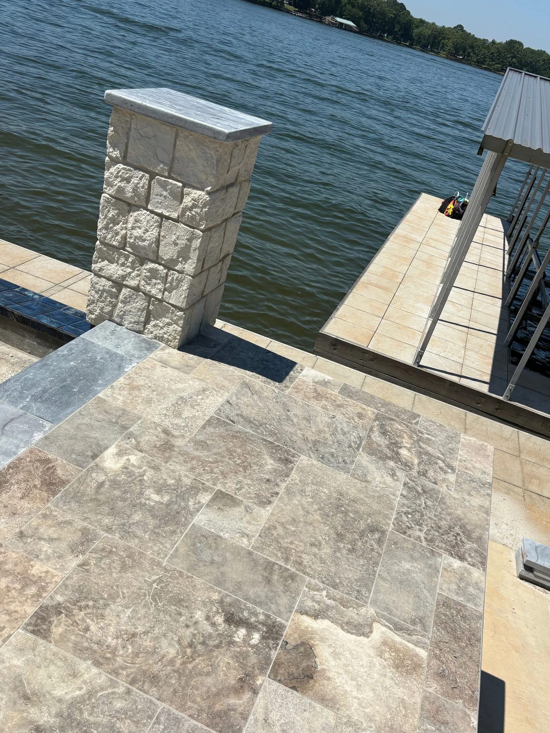 Travertine paving and a stone-veneer pillar on a dock over the water
