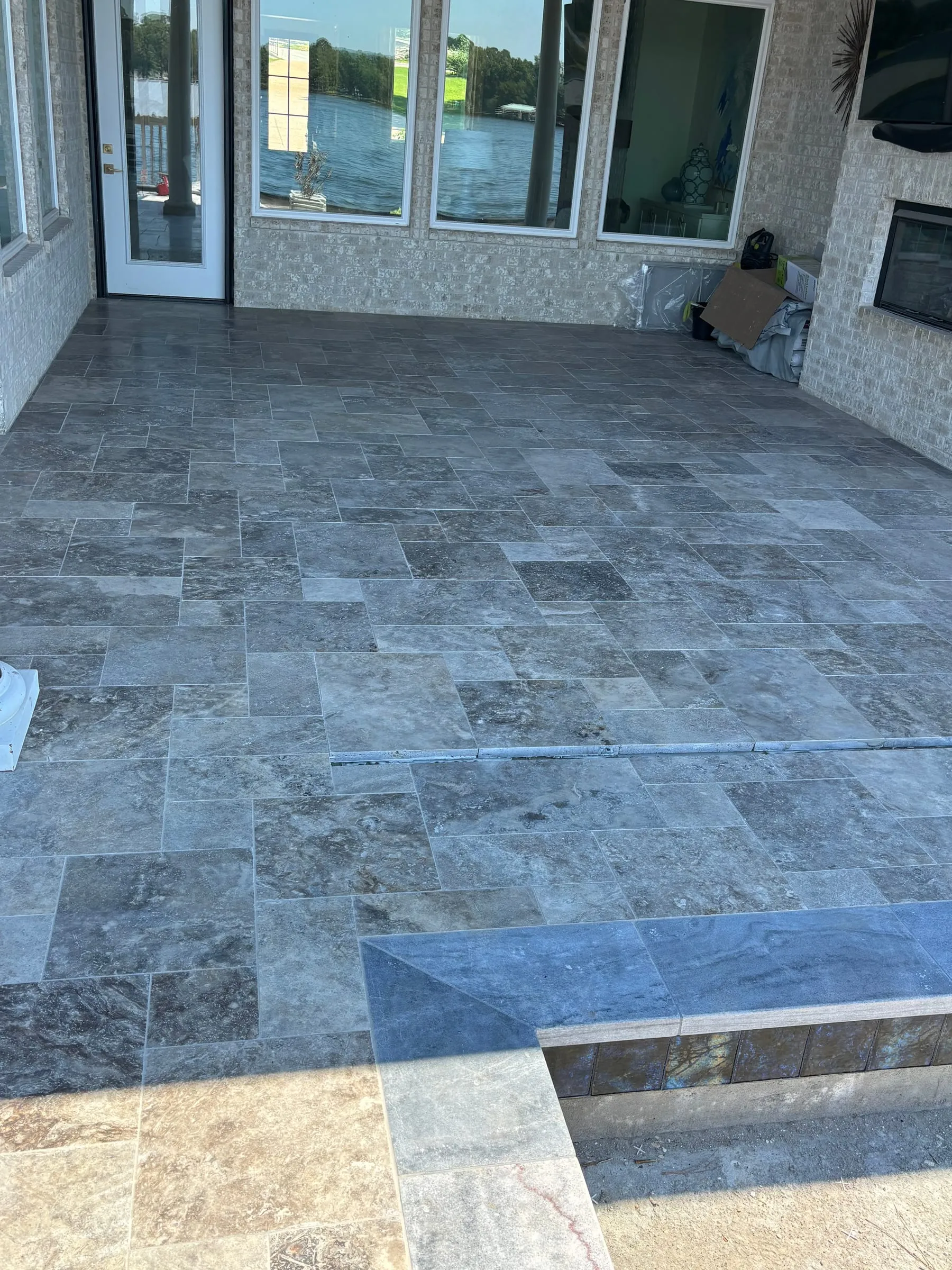 Covered patio floored in silver travertine in a French pattern