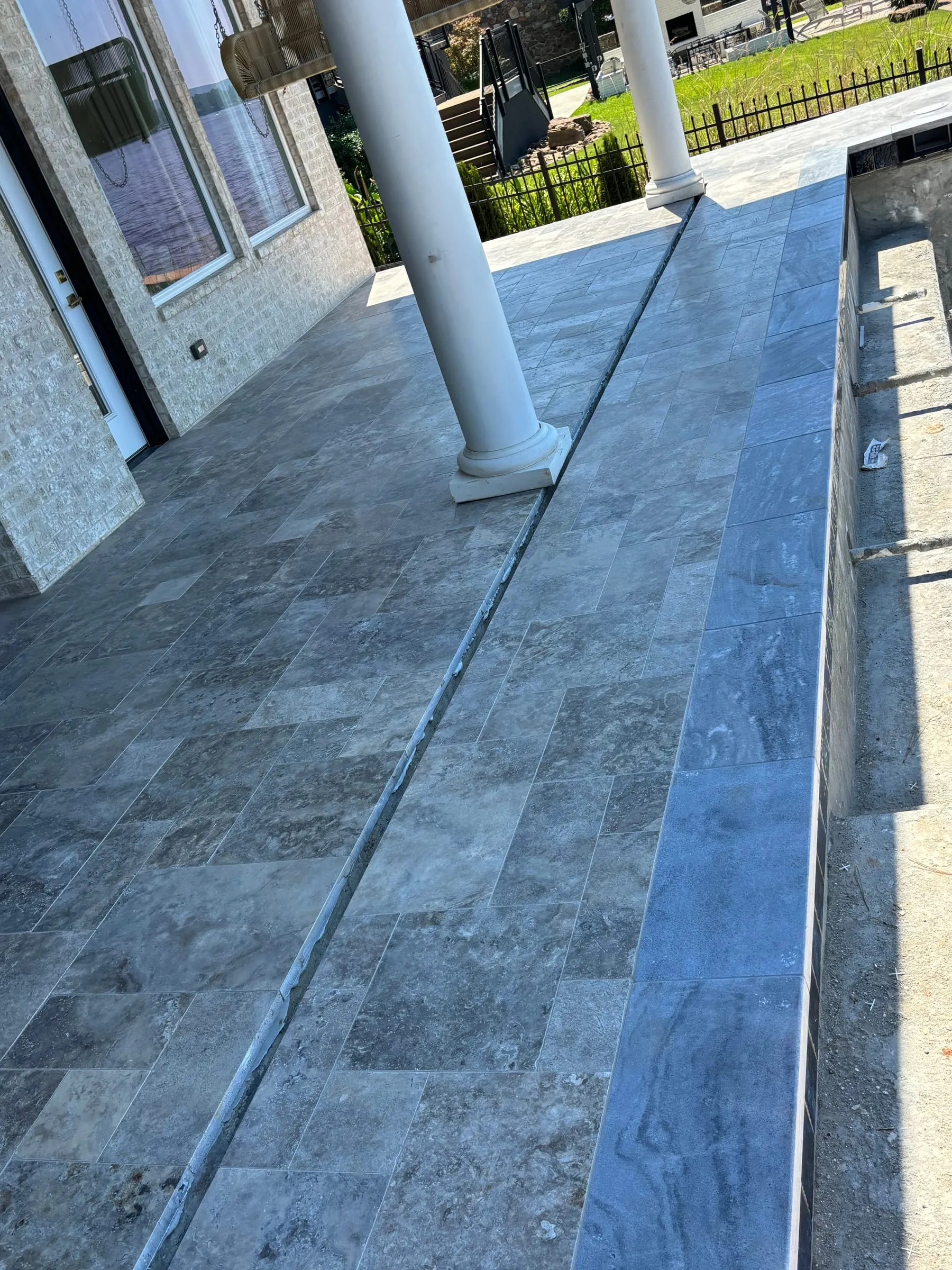 Travertine patio edge with a bullnose step along a covered porch